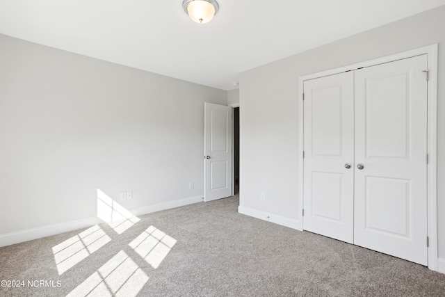 unfurnished bedroom with light colored carpet and a closet