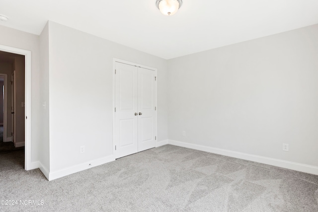 unfurnished bedroom featuring light carpet and a closet