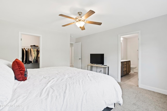 bedroom featuring a closet, light carpet, connected bathroom, a spacious closet, and ceiling fan