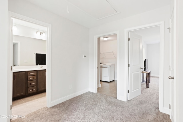 unfurnished bedroom featuring washer / dryer, a closet, light colored carpet, ensuite bath, and a walk in closet