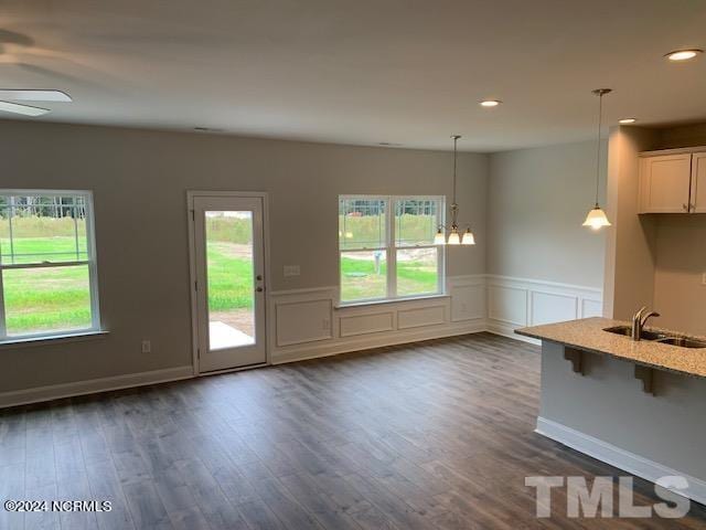 kitchen featuring decorative light fixtures, ceiling fan with notable chandelier, sink, dark wood-type flooring, and a kitchen bar