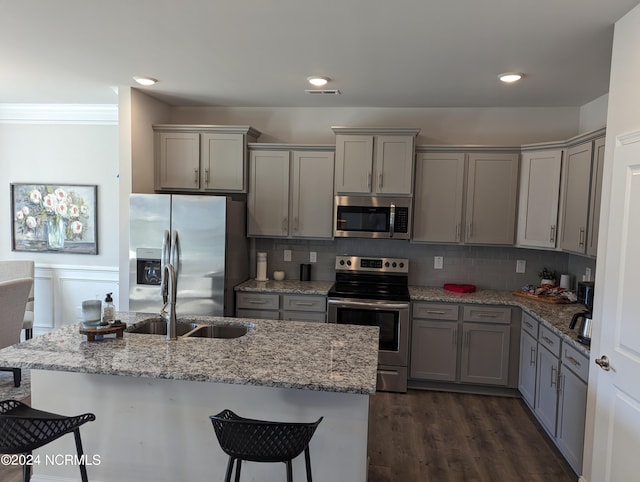 kitchen featuring gray cabinetry, appliances with stainless steel finishes, light stone counters, and dark hardwood / wood-style floors