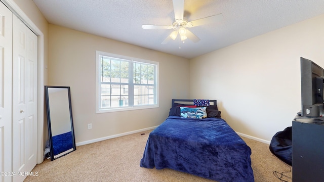 carpeted bedroom with a textured ceiling, ceiling fan, and a closet