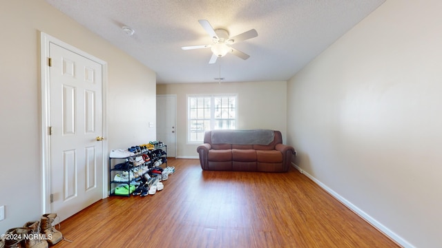 living area with ceiling fan, hardwood / wood-style floors, and a textured ceiling