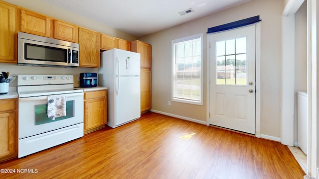 kitchen featuring light brown cabinetry, light hardwood / wood-style floors, and white appliances