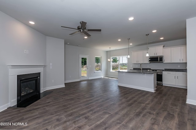 kitchen featuring a kitchen island with sink, hanging light fixtures, dark hardwood / wood-style flooring, white cabinetry, and stainless steel appliances