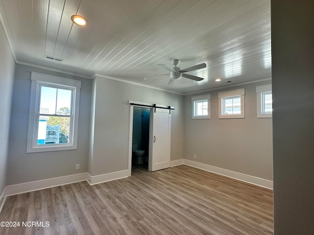 unfurnished bedroom with wooden ceiling, wood-type flooring, connected bathroom, ornamental molding, and a barn door