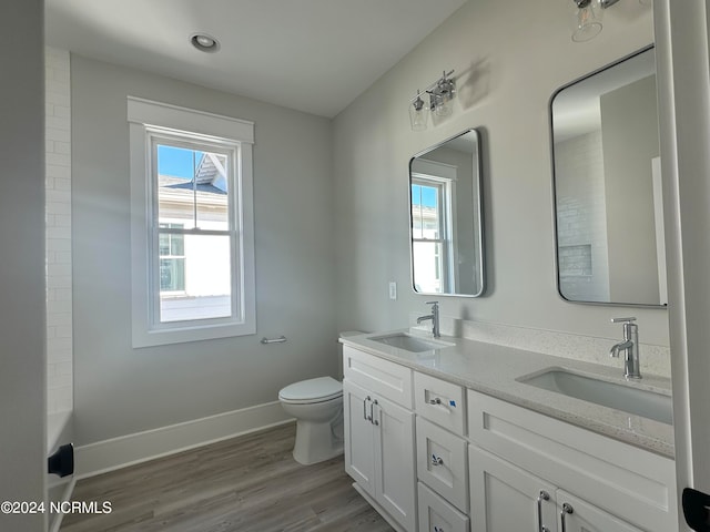 bathroom with vanity, toilet, hardwood / wood-style floors, and a bath