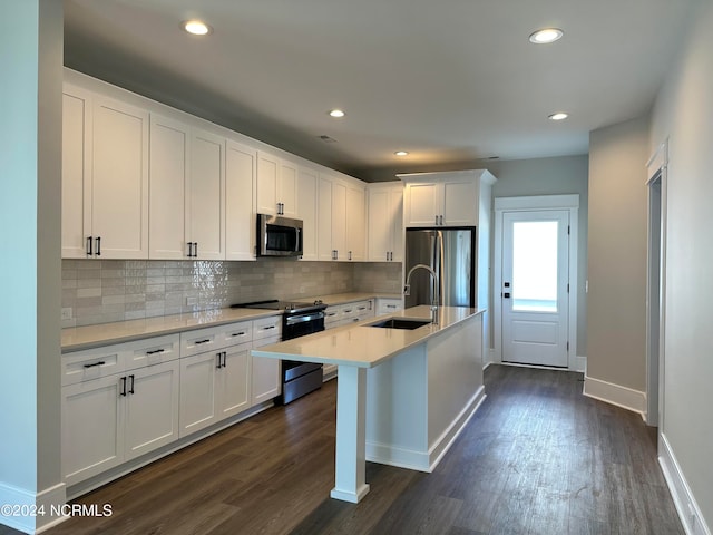 kitchen with white cabinetry, sink, dark hardwood / wood-style floors, appliances with stainless steel finishes, and a center island with sink