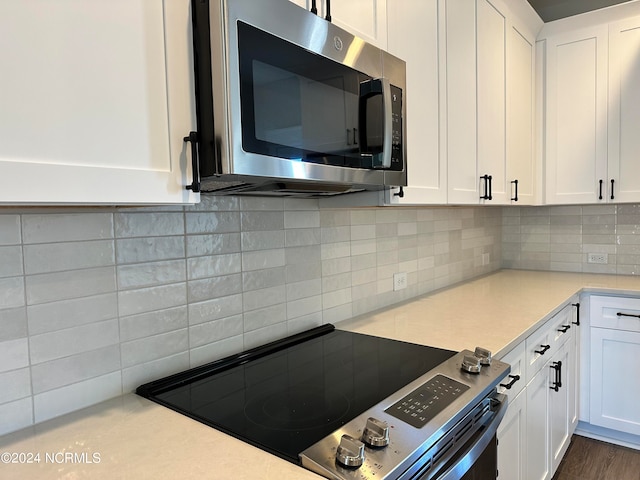 kitchen featuring appliances with stainless steel finishes, dark hardwood / wood-style flooring, white cabinets, and decorative backsplash