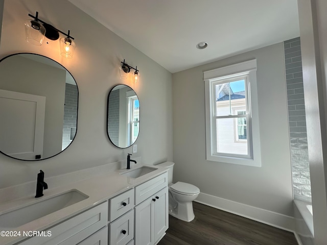 bathroom with vanity, toilet, a bath, and hardwood / wood-style flooring