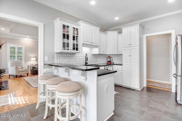 kitchen with glass insert cabinets, white cabinetry, a sink, and a breakfast bar area