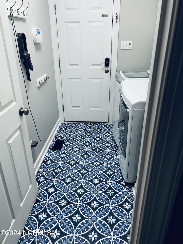 laundry area featuring laundry area, tile patterned floors, washing machine and dryer, and baseboards