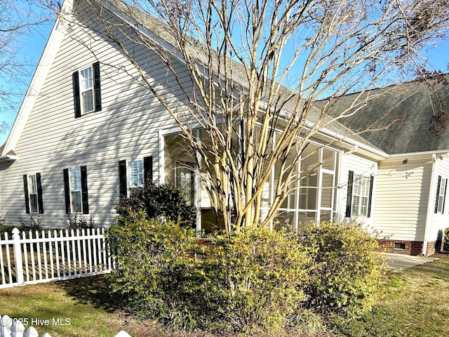 view of property exterior featuring a sunroom, fence, and roof with shingles