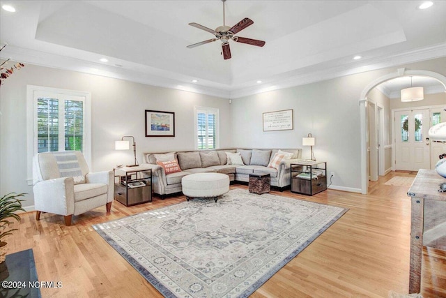 living room with arched walkways, a raised ceiling, and a wealth of natural light