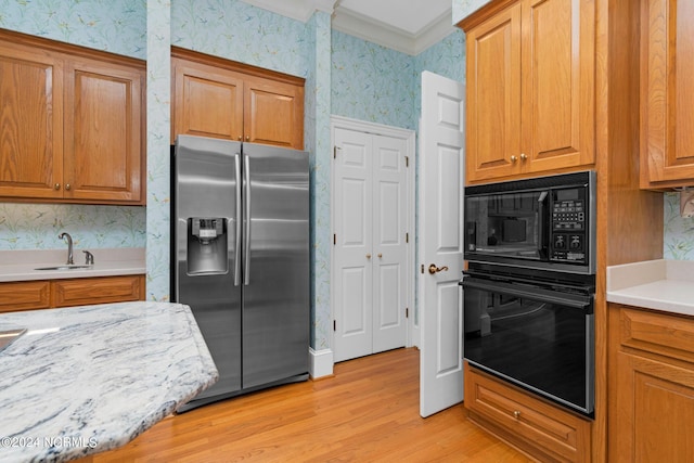 kitchen with sink, crown molding, light stone counters, light hardwood / wood-style flooring, and black appliances