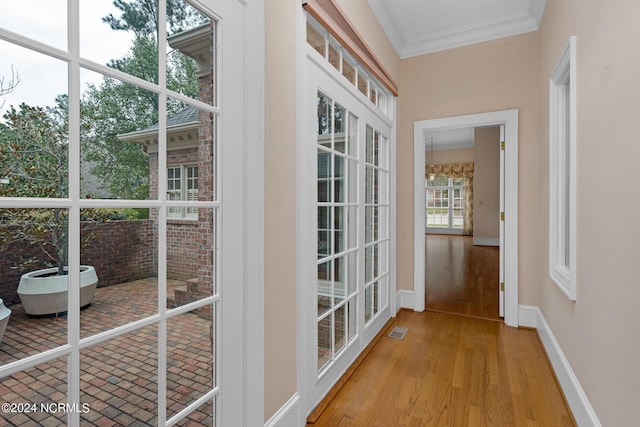 doorway to outside featuring ornamental molding and light wood-type flooring