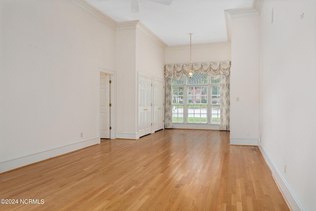 spare room with ornamental molding, ceiling fan with notable chandelier, and wood-type flooring