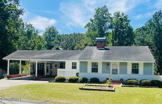 612 David St, Elizabethtown, NC 28337 - view of front of property with board and batten siding, concrete driveway, an attached carport, and a front lawn