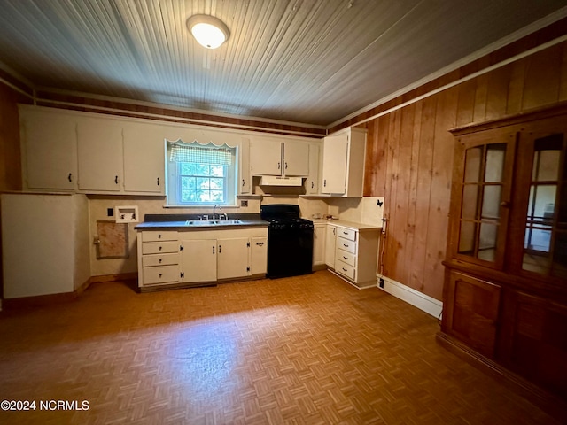 kitchen featuring white cabinets, wooden walls, black range with gas cooktop, a baseboard heating unit, and sink