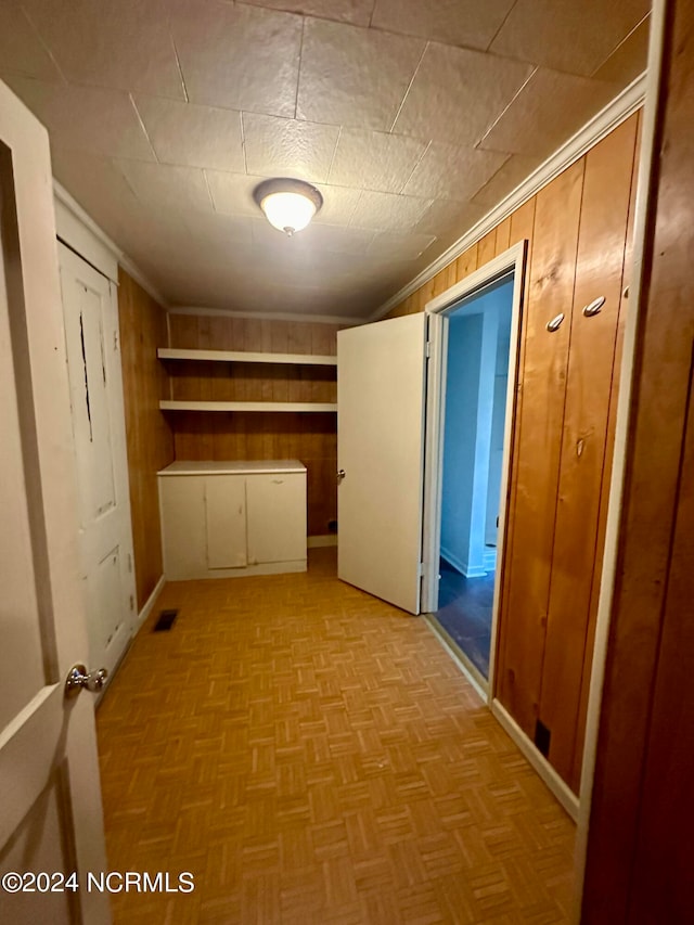 corridor featuring light parquet floors and wooden walls