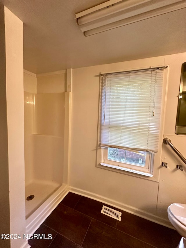 bathroom featuring toilet, walk in shower, and tile patterned floors