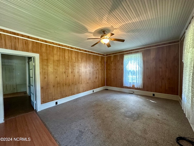 spare room featuring carpet, ceiling fan, and wooden walls