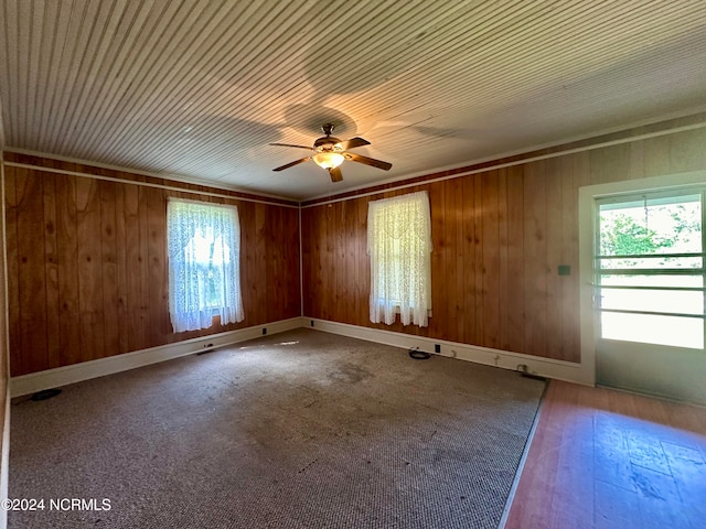 unfurnished room with ceiling fan and wood walls