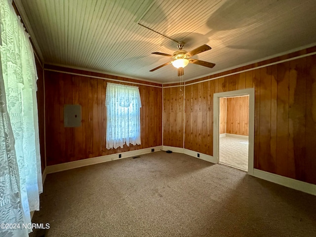 carpeted spare room with wood walls and ceiling fan