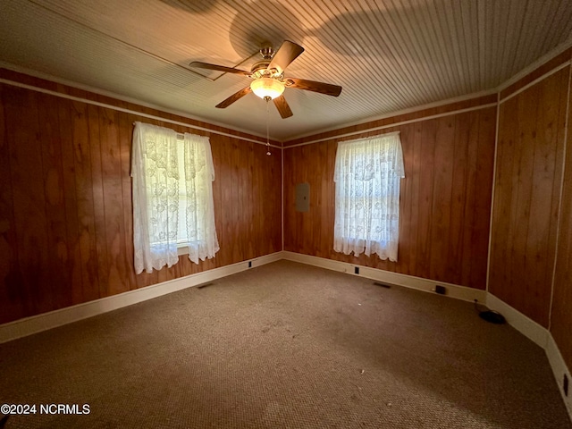 carpeted spare room with ceiling fan and wooden walls