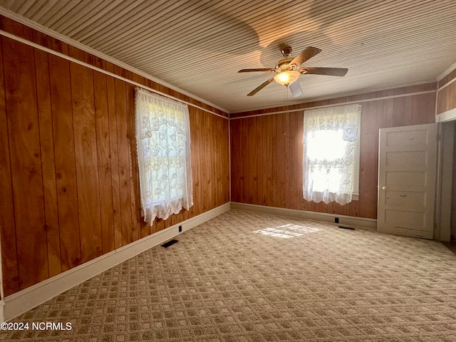 empty room with wood walls, ceiling fan, and carpet floors