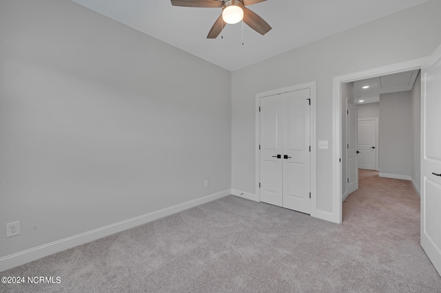 unfurnished bedroom with light colored carpet, ceiling fan, and a closet