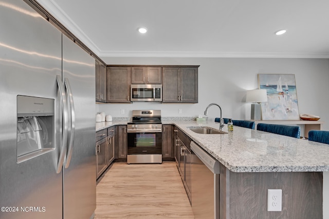 kitchen with crown molding, kitchen peninsula, sink, appliances with stainless steel finishes, and light hardwood / wood-style floors