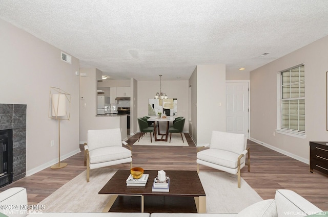 living room featuring a fireplace, a textured ceiling, light hardwood / wood-style flooring, and a chandelier