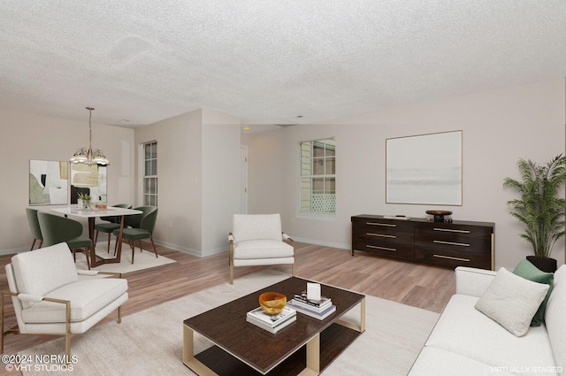 living room featuring light wood-type flooring, a textured ceiling, and an inviting chandelier