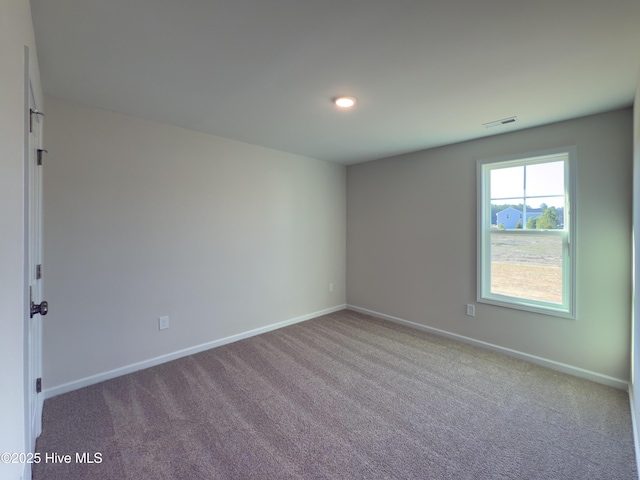 carpeted spare room with visible vents and baseboards