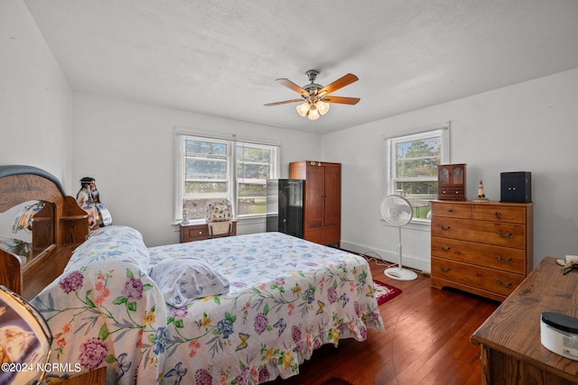 bedroom with a textured ceiling, ceiling fan, and dark hardwood / wood-style flooring