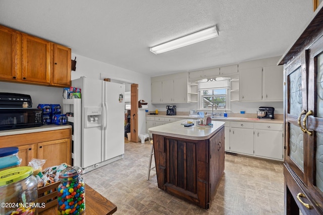 kitchen with sink, a center island, white cabinets, and white refrigerator with ice dispenser