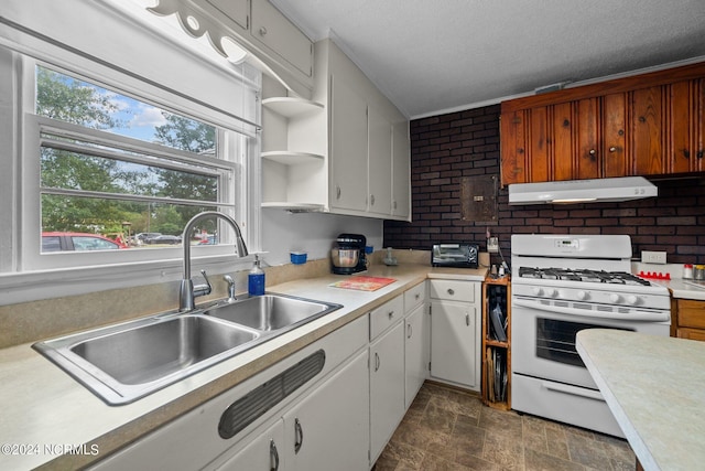 kitchen with brick wall, white gas stove, sink, and white cabinets