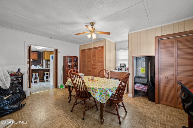 dining space with ceiling fan and wooden walls