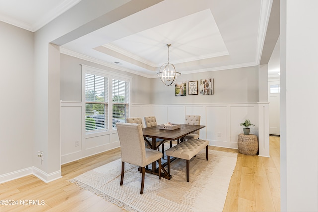 dining area featuring light hardwood / wood-style flooring, a tray ceiling, and crown molding