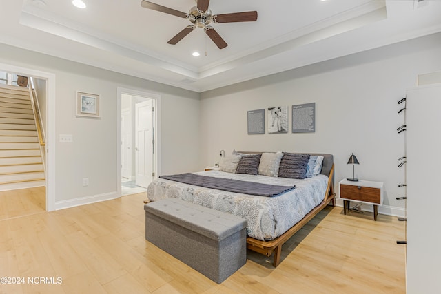 bedroom featuring ceiling fan, a raised ceiling, ornamental molding, and hardwood / wood-style floors