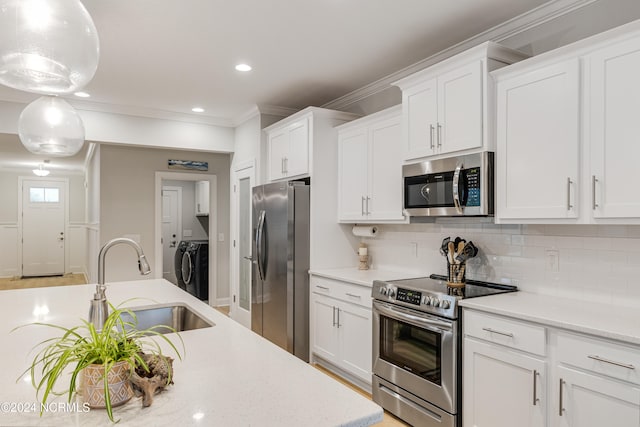 kitchen with hanging light fixtures, independent washer and dryer, stainless steel appliances, sink, and white cabinetry