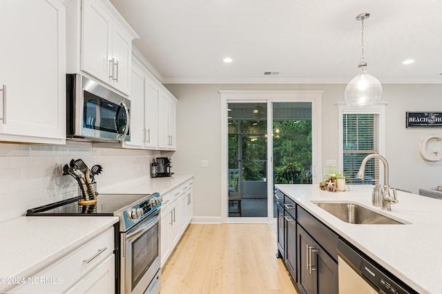 kitchen featuring white cabinets, hanging light fixtures, light hardwood / wood-style flooring, sink, and stainless steel appliances