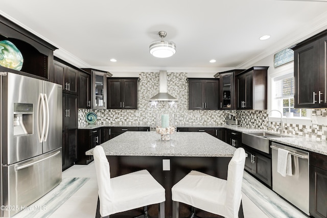 kitchen with tasteful backsplash, a breakfast bar area, stainless steel appliances, wall chimney range hood, and a sink