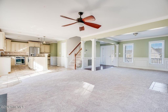 unfurnished living room with light carpet, crown molding, and ceiling fan