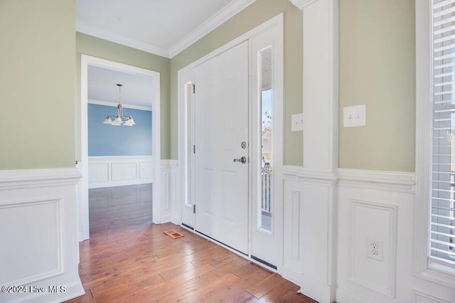 foyer featuring a chandelier, wood-type flooring, and ornamental molding