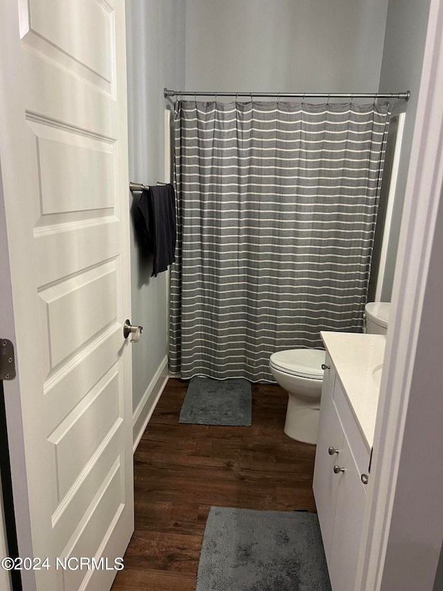 bathroom with a shower with shower curtain, hardwood / wood-style flooring, vanity, and toilet