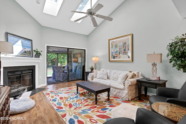 living room featuring ceiling fan, high vaulted ceiling, hardwood / wood-style flooring, and a skylight