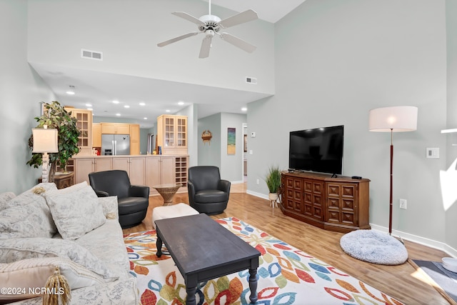 living room with ceiling fan, high vaulted ceiling, and light hardwood / wood-style floors